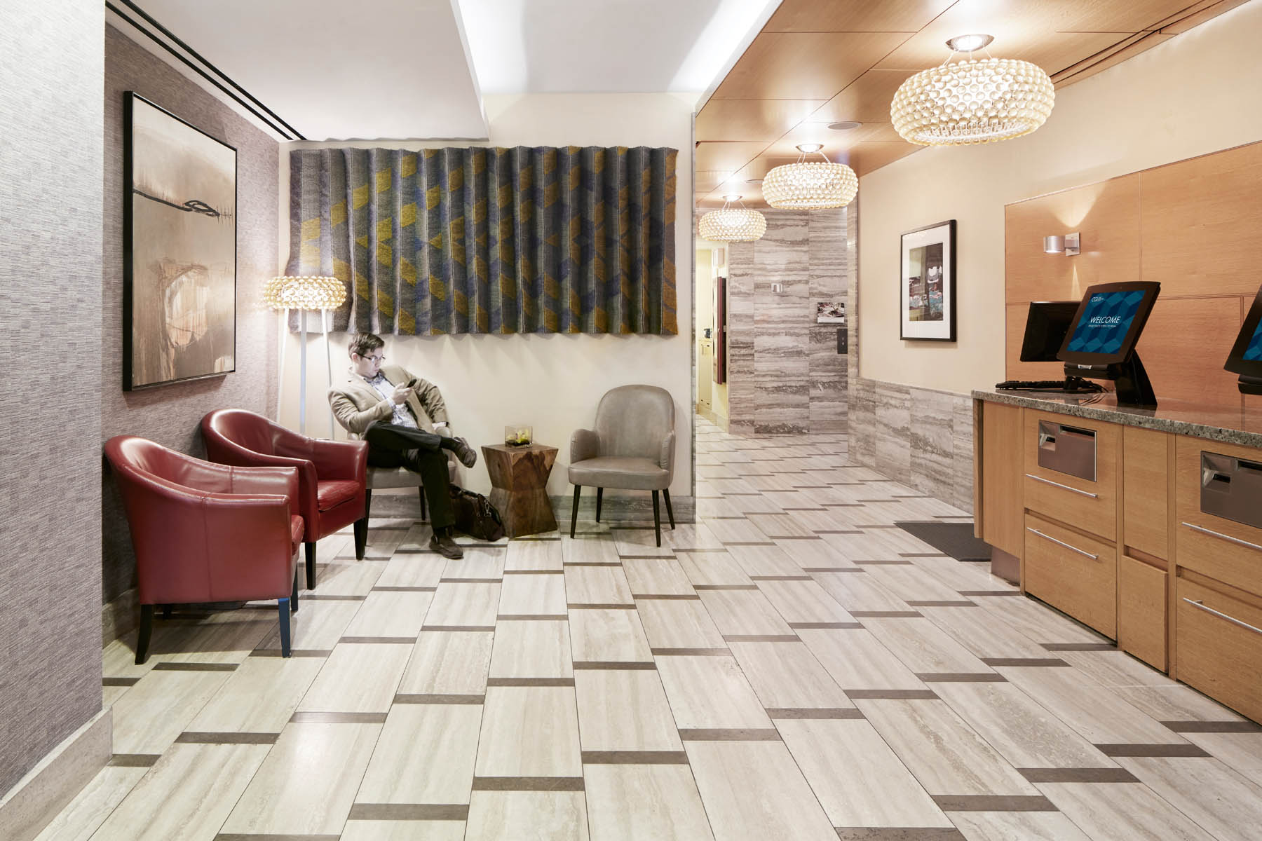 A hotel lobby with a reception desk, seating area, and chairs