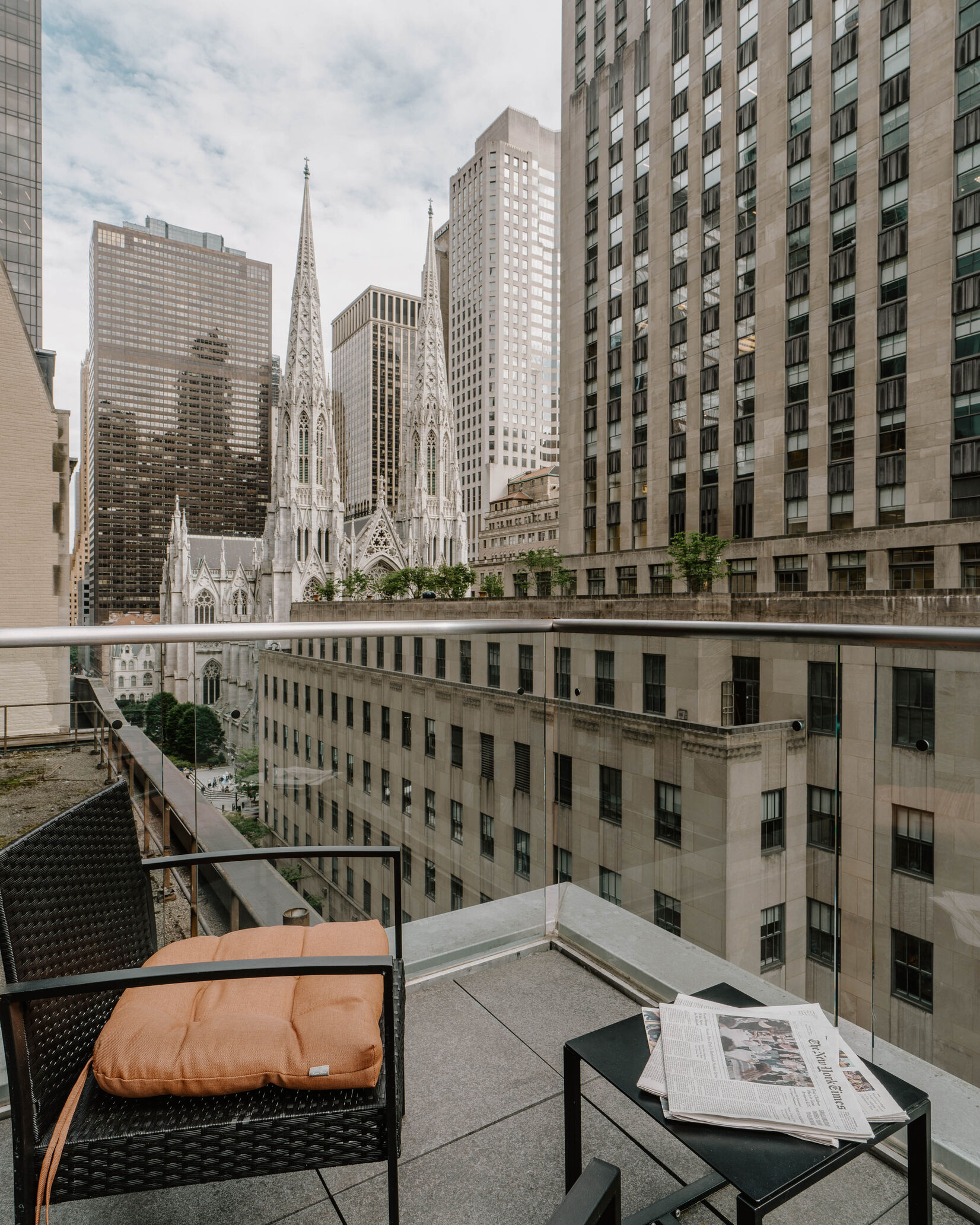A balcony with a glass railing overlooking a cityscape with a church in the distance.